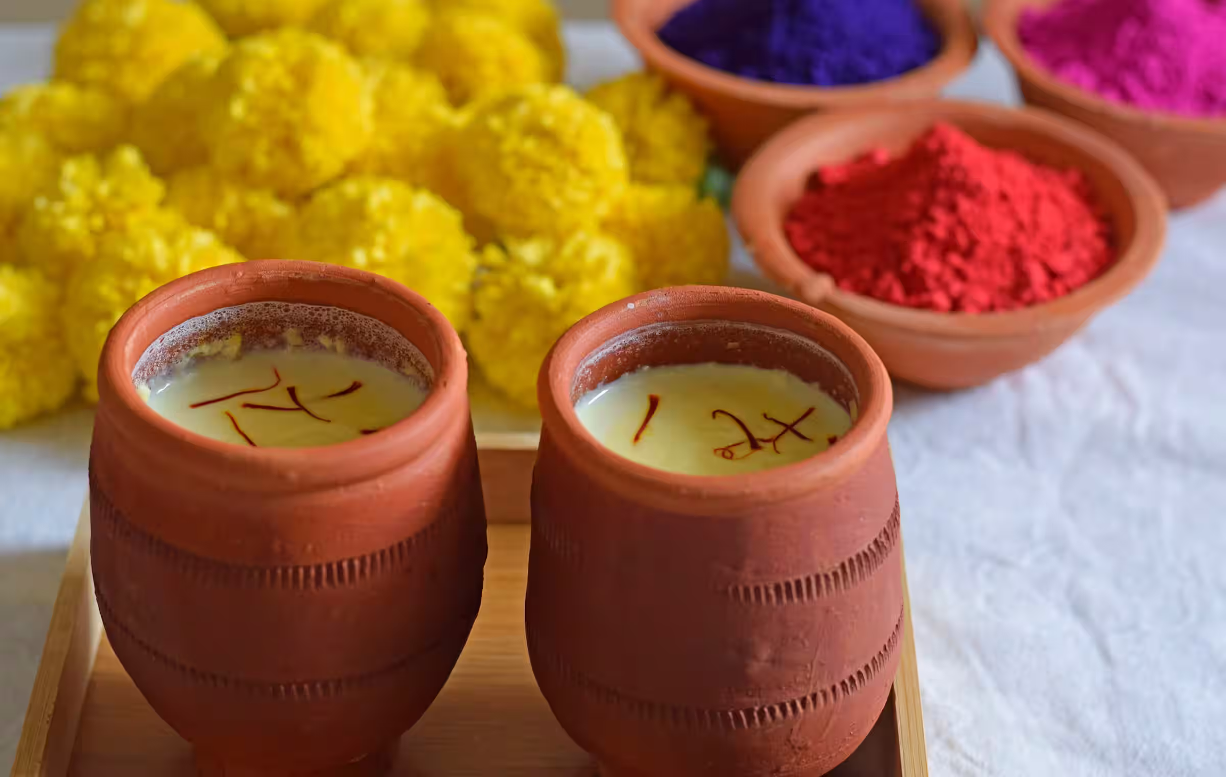 warm saffron milk in clay cups with saffron strands nuts and yellow flowers